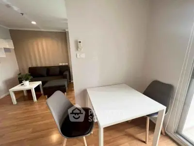 Modern apartment interior with cozy living room and dining area, featuring sleek furniture and wooden flooring.
