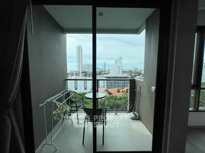 Modern balcony with city view, featuring a cozy seating area and laundry rack, perfect for urban living.