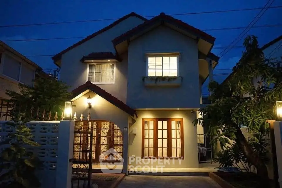 Charming two-story house with warm evening lights and inviting facade.