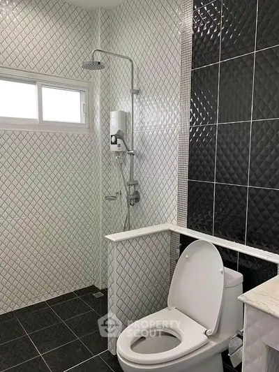 Modern bathroom with stylish black and white tiles and sleek fixtures.