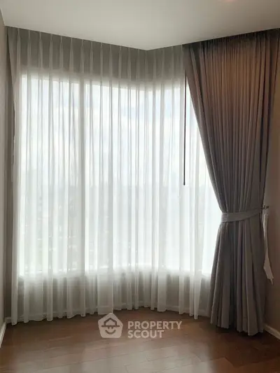 Elegant corner unit with floor-to-ceiling windows and luxurious curtains in a modern apartment.
