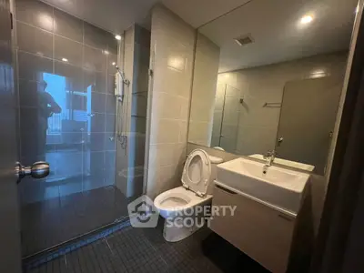 Modern bathroom with glass shower and sleek fixtures in contemporary apartment.