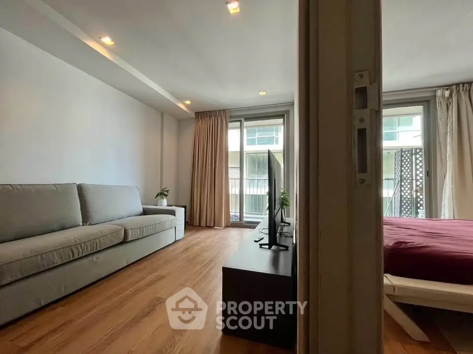 Modern living room with wooden flooring and large windows in a stylish apartment.