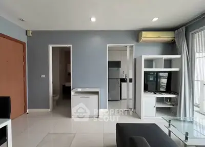 Modern living room with sleek design, featuring a glass coffee table, TV unit, and air conditioning.