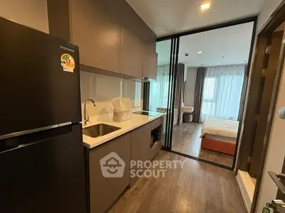 Modern apartment kitchen with sleek design and view into cozy bedroom