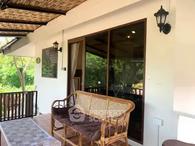 Charming patio with rustic rattan furniture and lush garden view, perfect for relaxing outdoors.