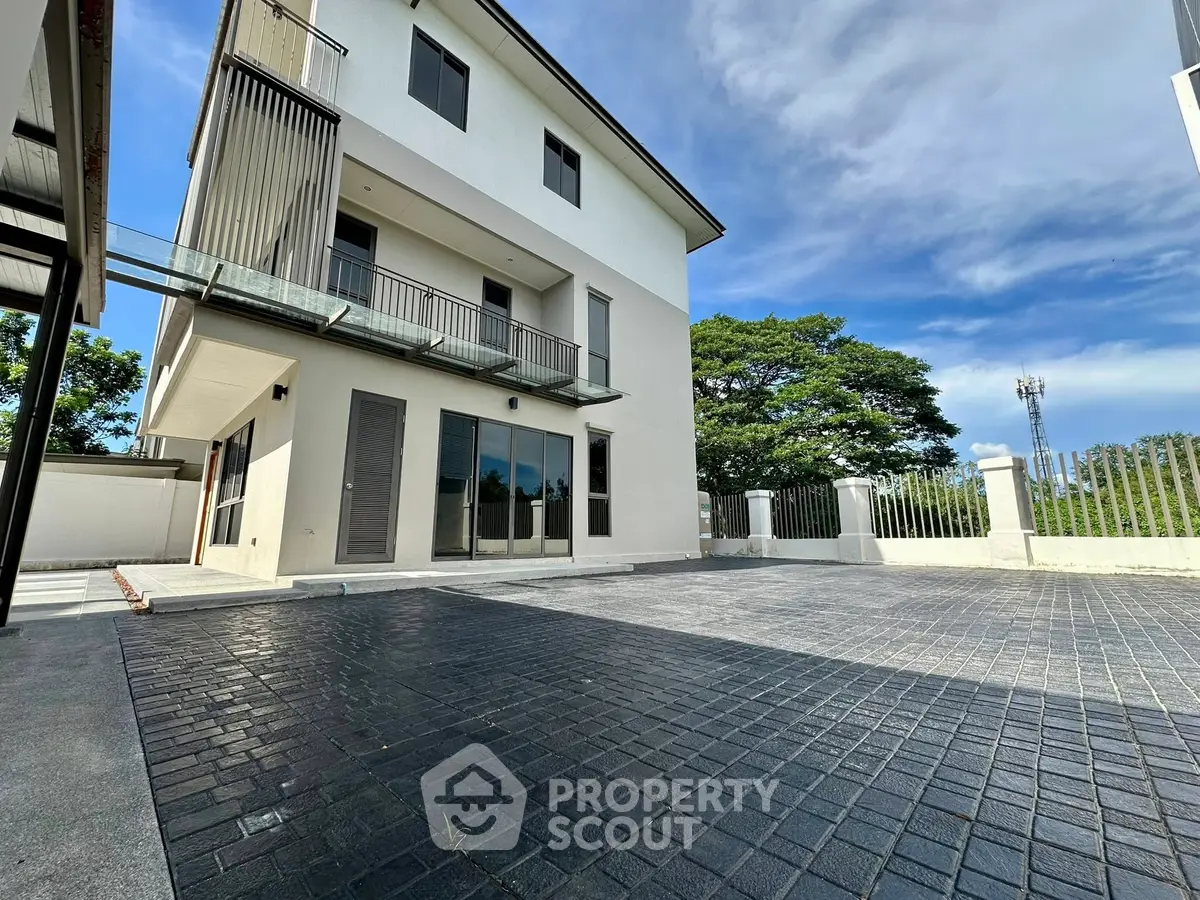 Modern three-story building with spacious driveway and lush greenery, perfect for luxurious living.