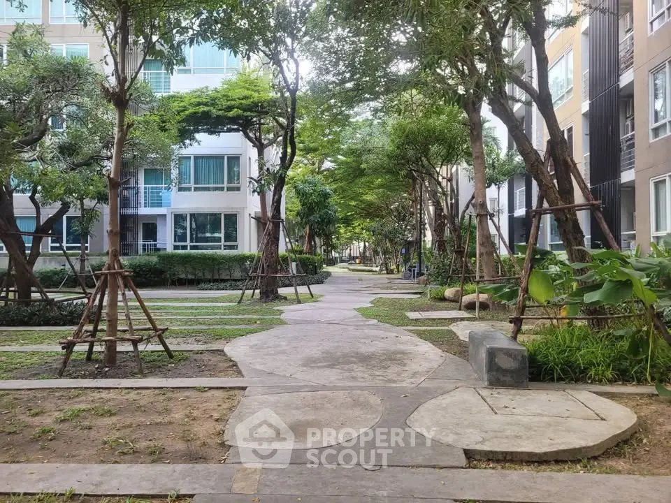 Charming garden pathway in modern residential complex with lush greenery and contemporary architecture.