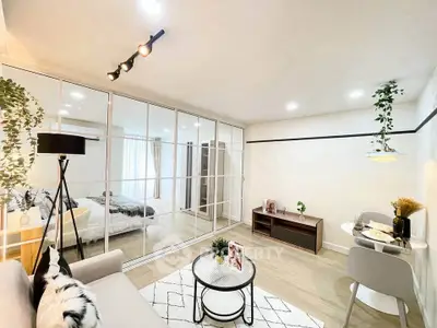 Modern open-plan living room with stylish decor and glass partition to bedroom
