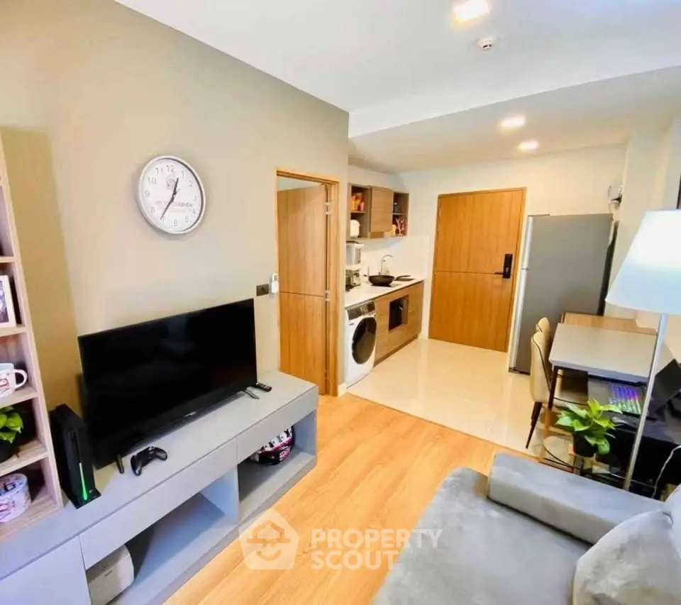 Modern living room with open kitchen, featuring sleek appliances and stylish decor.