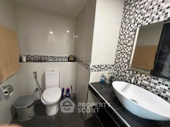 Modern bathroom with stylish black and white mosaic tiles and sleek fixtures.