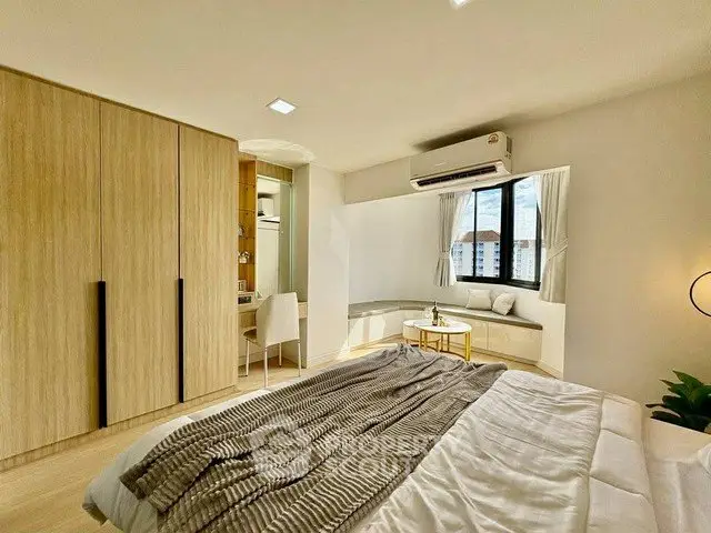 Spacious bedroom with modern design, large window, and built-in wardrobe offering city views.