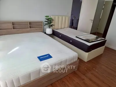 Spacious bedroom with modern design and wooden flooring, featuring two comfortable beds and stylish decor.
