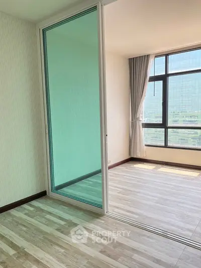 Bright modern room with large window and sliding glass door, featuring elegant flooring and city view.