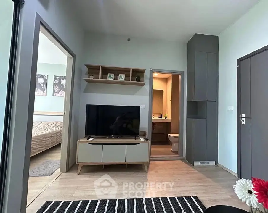Modern living room with TV and open view to bedroom and bathroom