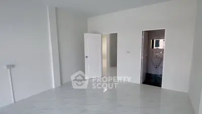 Spacious empty room with white walls and marble flooring, featuring open doorways to adjacent areas.