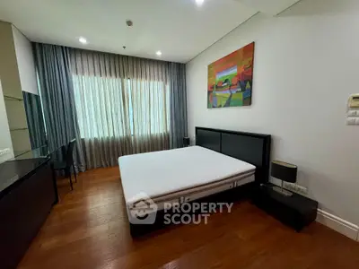 Spacious bedroom with modern decor and large window in luxury apartment.