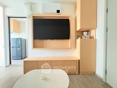 Modern living room with built-in TV unit and view into sleek kitchen