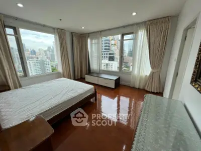 Spacious bedroom with large windows offering stunning city views in a modern apartment.