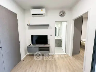 Modern living room with TV, air conditioning, and wooden flooring in a stylish apartment.