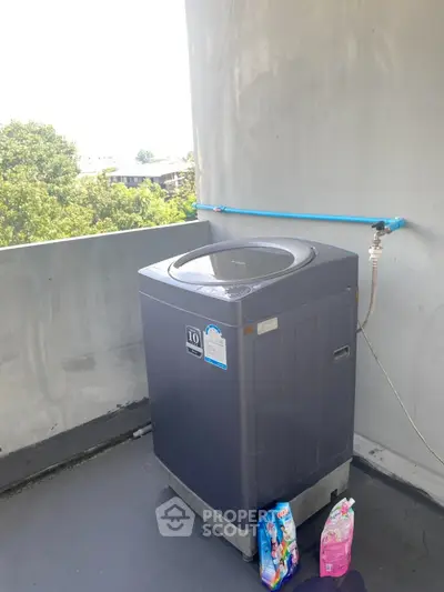 Outdoor washing machine setup on balcony with city view