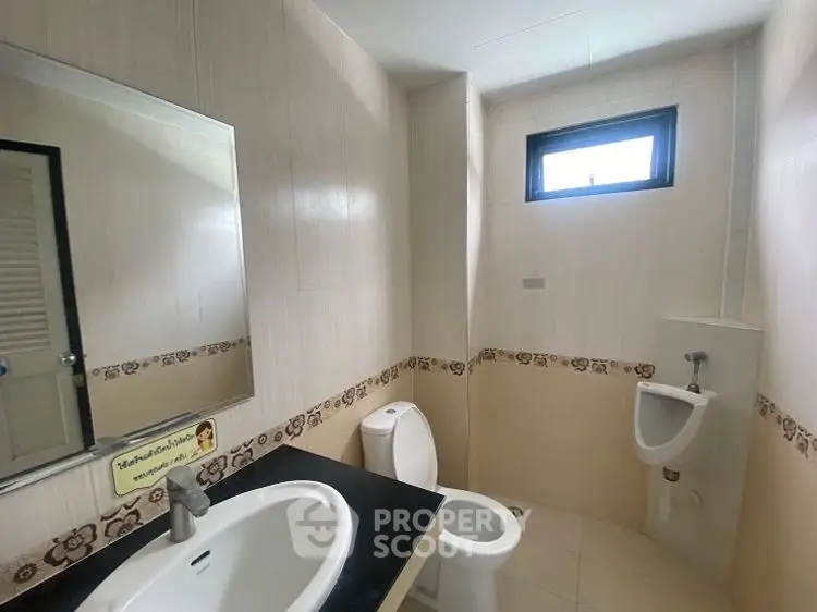 Modern bathroom with sleek fixtures and natural light from a small window.