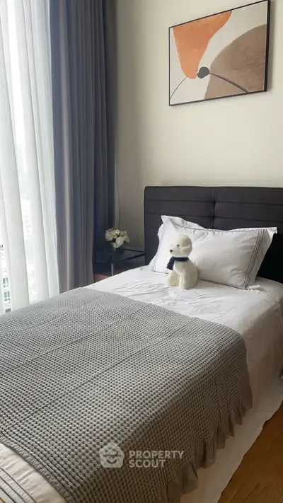 Cozy bedroom with modern decor and plush bedding, featuring a large window with natural light.