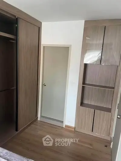 Modern bedroom with wooden flooring and built-in wardrobe, showcasing sleek design and ample storage space.