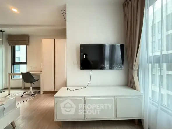 Modern living room with wall-mounted TV and stylish furniture in a bright apartment.