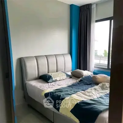Modern bedroom with stylish bed and large window offering natural light.