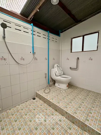 Spacious bathroom with elevated shower and toilet area, featuring tiled walls and floor.