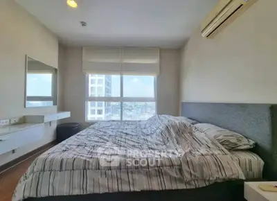 Spacious bedroom with large window offering city views and modern furnishings.