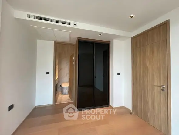 Modern minimalist bedroom with ensuite bathroom and wooden flooring