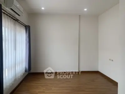 Spacious empty room with wooden flooring and large window