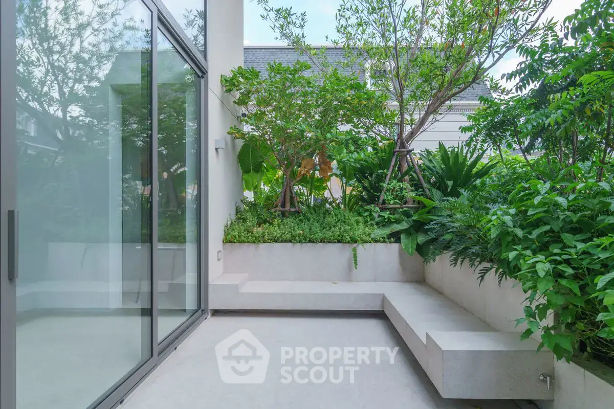 Modern outdoor patio with lush greenery and sleek glass doors