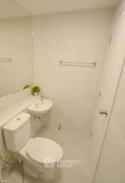 Modern minimalist bathroom with white tiles and compact fixtures
