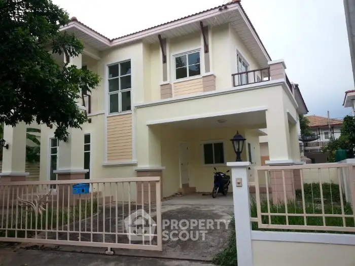 Charming two-story house with gated entrance and lush greenery, perfect for family living.