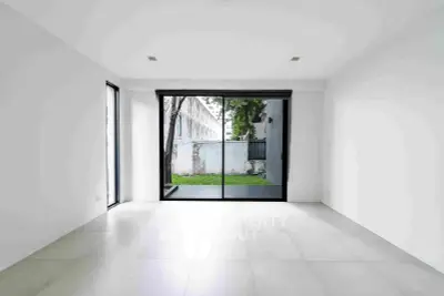 Spacious empty room with large sliding glass doors opening to a private garden area.