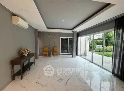 Spacious modern living room with marble flooring and large windows overlooking a garden.