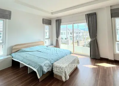 Spacious bedroom with large windows and balcony offering a scenic view in a modern home.