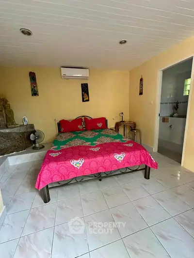 Cozy bedroom with vibrant decor and air conditioning, featuring tiled flooring and a glimpse into an adjoining bathroom.