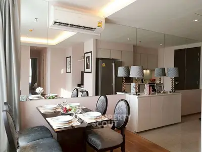 Modern dining area with elegant table setting and mirrored wall in stylish apartment.
