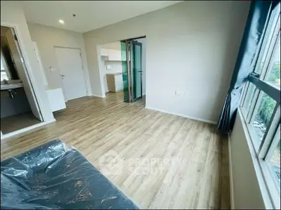 Spacious modern apartment with wooden flooring and large windows offering natural light.