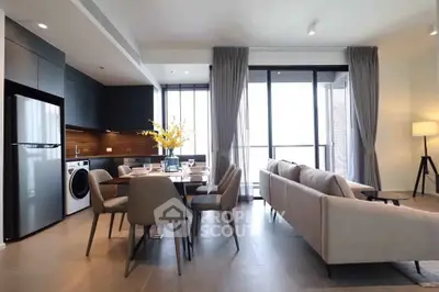 Modern open-plan living room with sleek kitchen and dining area, featuring floor-to-ceiling windows and elegant decor.