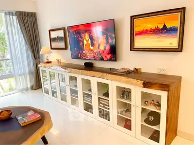 Stylish living room with modern decor and large TV, perfect for entertainment.