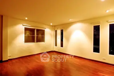 Spacious empty room with polished wooden floors and ambient lighting, perfect for customization.