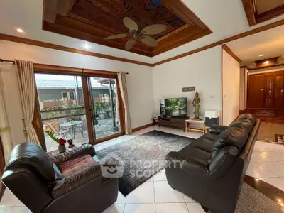 Spacious living room with leather sofas and garden view, perfect for relaxation.