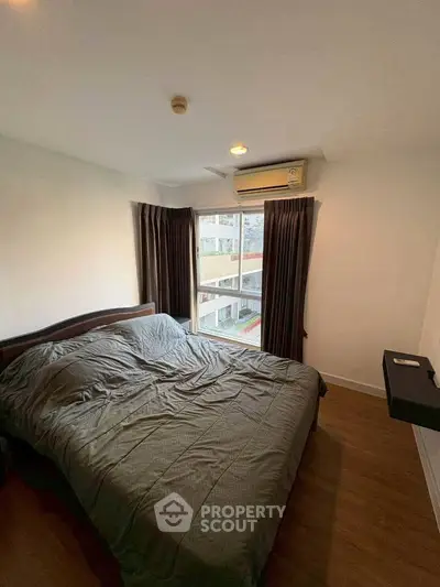 Cozy bedroom with large window and air conditioning in modern apartment.