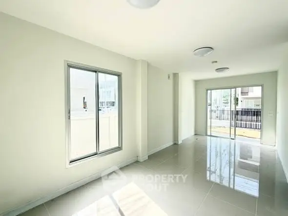 Spacious and bright living room with large windows and modern tile flooring.