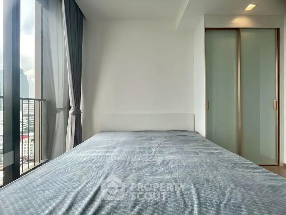 Modern bedroom with large window and city view, featuring sleek sliding closet doors.